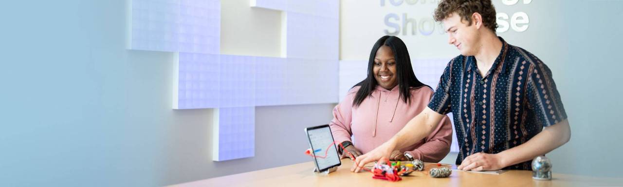 2 students standing at a table looking at an ipad